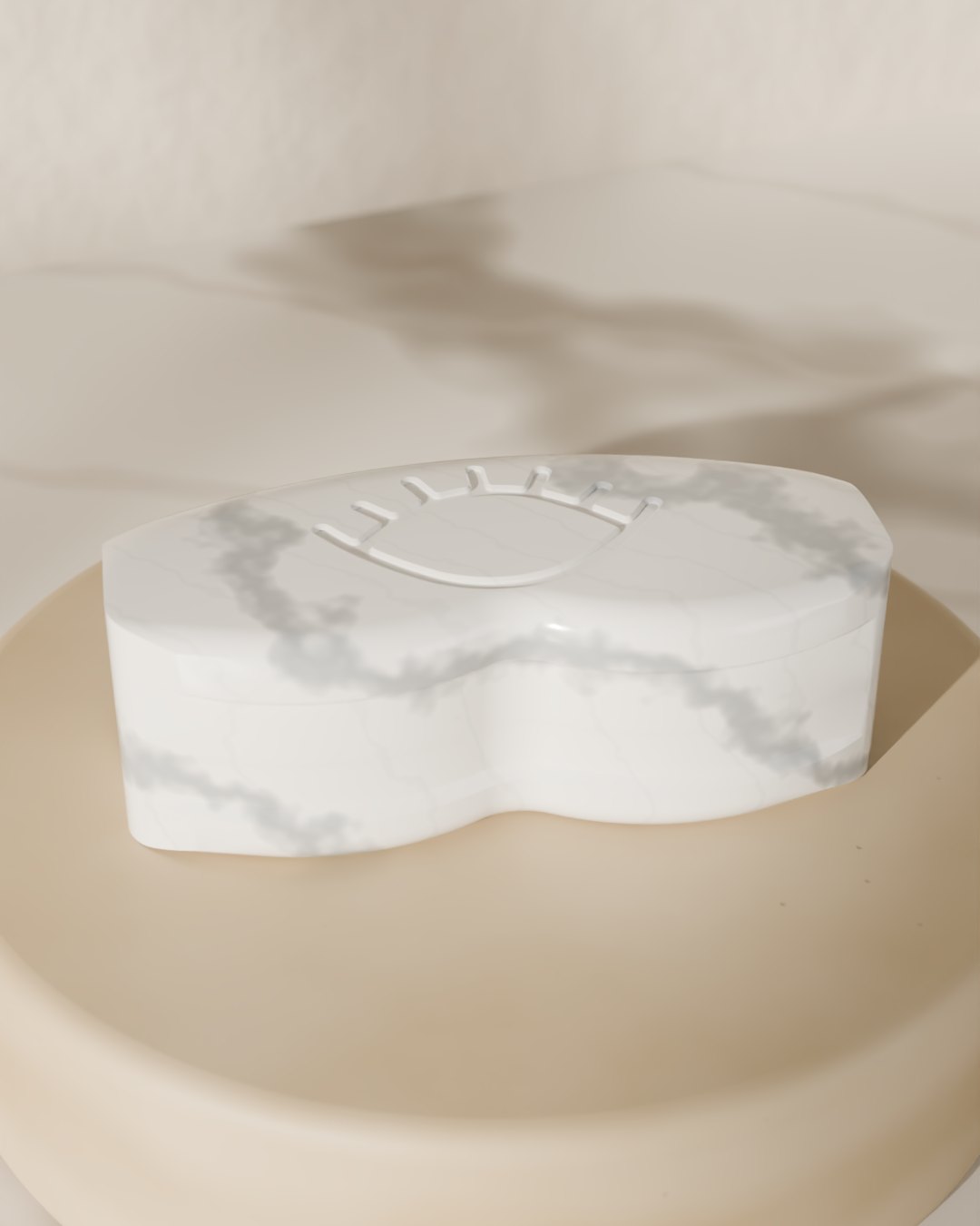 A closed white marble Lenspod case with grey veining and an engraved eye on the lid, resting on a round beige stone plinth in soft sunlight.